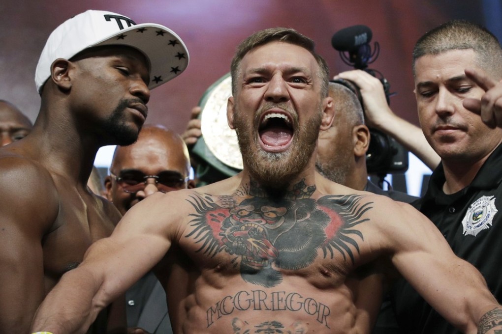 \Conor McGregor, center, stands next to Floyd Mayweather Jnr during their weigh-in. Photo: AP