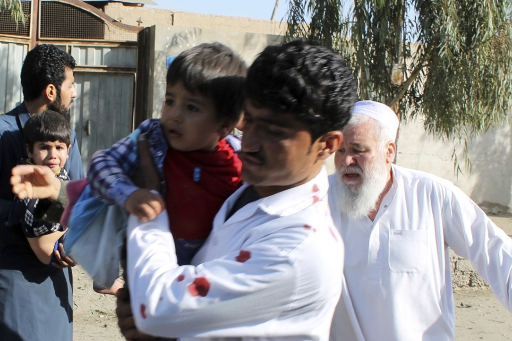 Men carry children away from an explosion site in Lashkar Gah, the capital of the southern Helmand province, in Afghanistan on Saturday. Photo: AP
