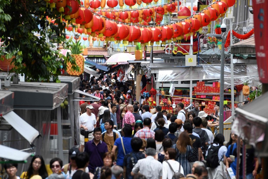 People walk along a crowded alleyway past stalls selling gifts and decorative items in the Chinatown district in Singapore. Photo: AFP