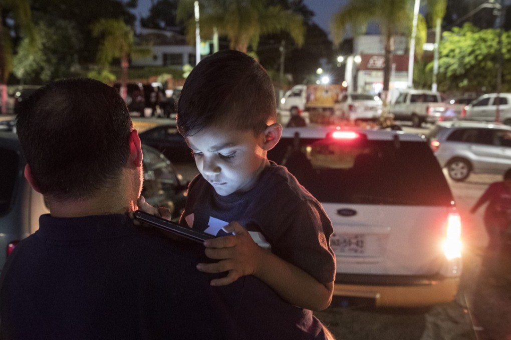Alejandro Madrigal, 3, plays games on an iPad as dad Ricardo carries him back to the car after an outing at Lake Chapala, Mexico. Photo: Tribune News Service