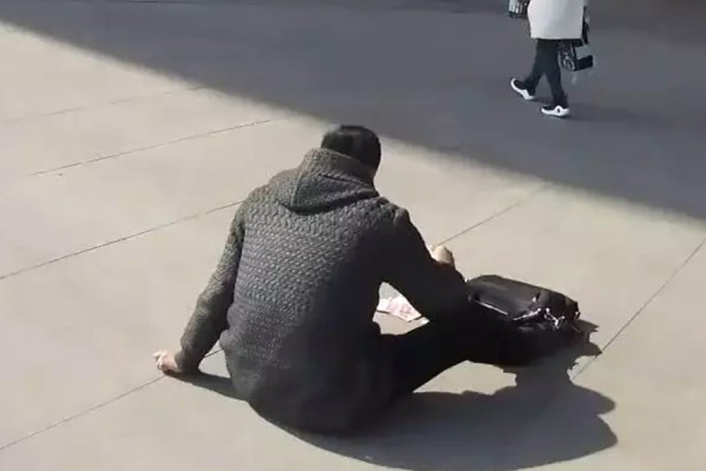 Unable to speak, a man having a heart attack tries to attract attention by putting money on the ground outside a railway station in Shijiazhuang, Hebei province. Photo: Kaixian.tv