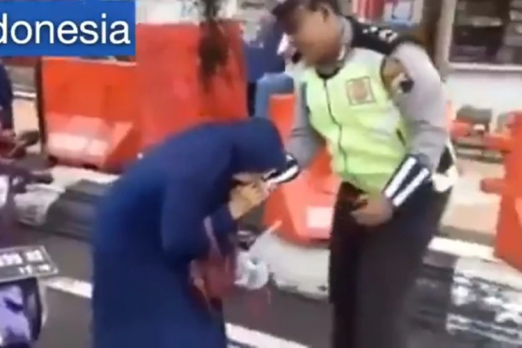 A screengrab from a video posted on Facebook shows a motorcyclist in Ipilo, North Sulawesi, who was stopped by a policeman for not wearing a helmet. Photo: Policevideo/Facebook