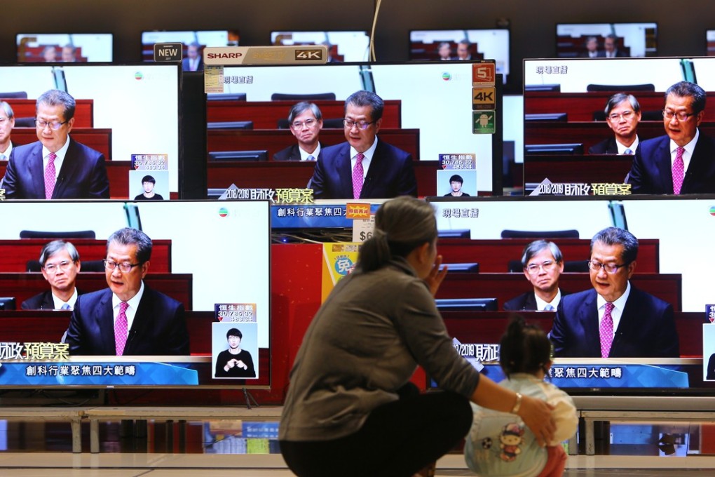 A woman and a child watch the live broadcast of Financial Secretary Paul Chan Mo-po delivering the 2018-2019 budget, in Kowloon Bay. The budget offered tax breaks to the middle-class, but no substantial overhaul of the tax structure. Photo: Winson Wong