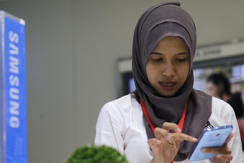 A customer uses a smartphone inside a Samsung showroom in Jakarta, Indonesia. Chinese start-up Apus found that online financial services are popular phone applications in Indonesia. Photo: Reuters