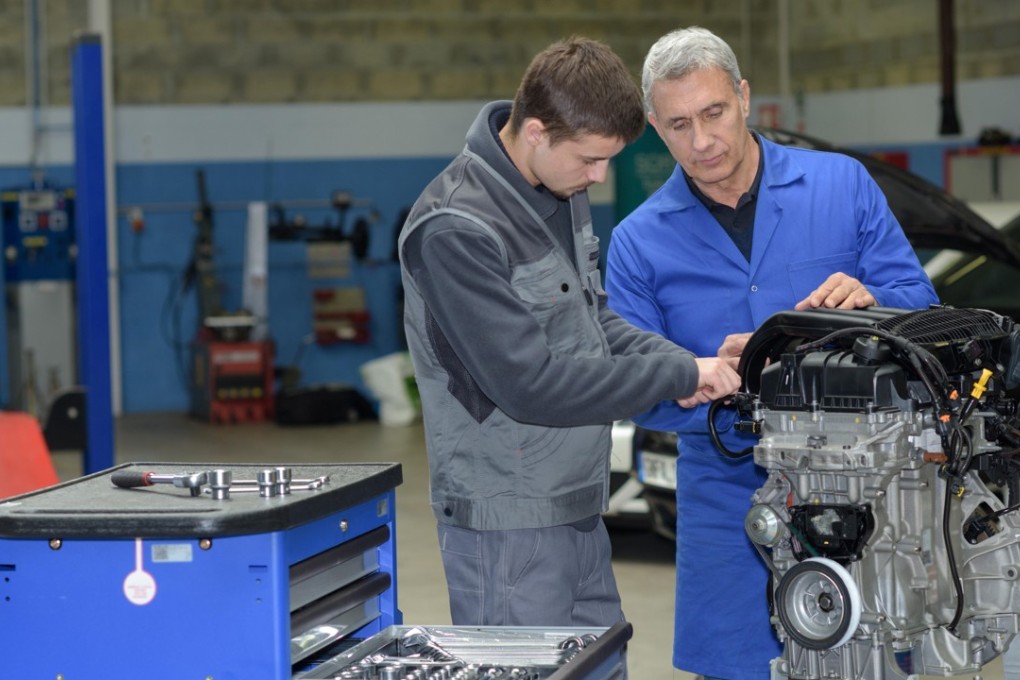 An apprentice repairing a car with a mentor. Apprentices often shadow a more senior employee so they can learn the business, ask specific questions and observe how to develop positive relationships at work. Photo: Alamy