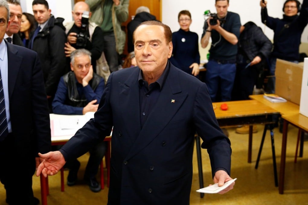 Former Italian premier Silvio Berlusconi listens to reporters at a polling station in Milan. Photo: Reuters