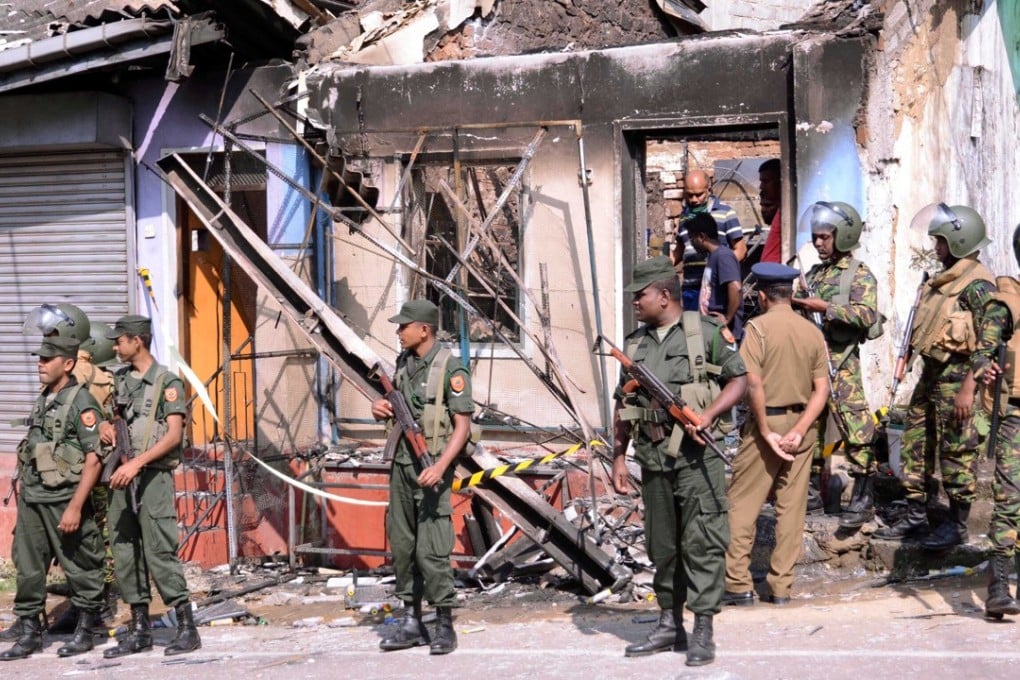 Sri Lanka's Special Task Force and Police officers stand guard near a burnt house in Sri Lanka. Photo: Reuters
