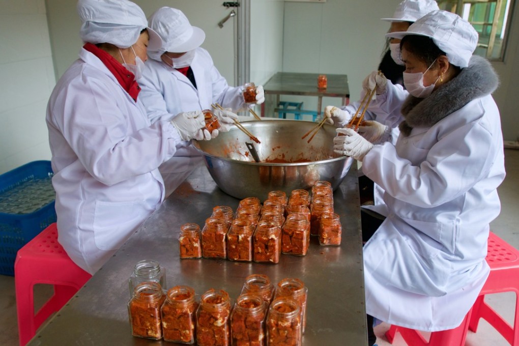 A group of middle-aged and older village people from Wan'an county in Jiangxi province work at a small factory that produces the “Luo Doudou” brand of fermented bead curd, which is sold online through Taobao Marketplace and WeChat. Photo: Tom Wang