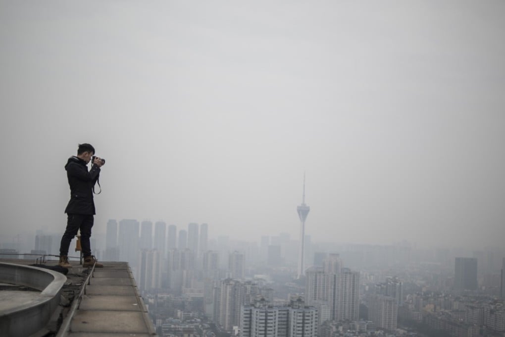 Yan Lei stands on the roof of a skyscraper, just metres from the edge, as he takes pictures of Chengdu. Photo: AFP