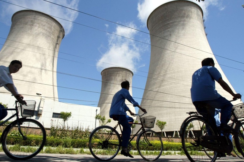 Cyclists ride past cooling towers at a coal-fired power station on the outskirts of Beijing. Photo: AP