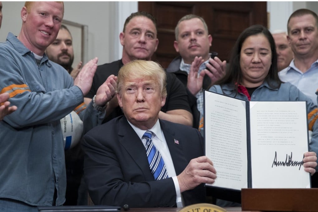 US President Donald Trump signs a presidential proclamation on tariffs with steel workers in the Roosevelt Room of the White House in Washington on Thursday. Photo: EPA