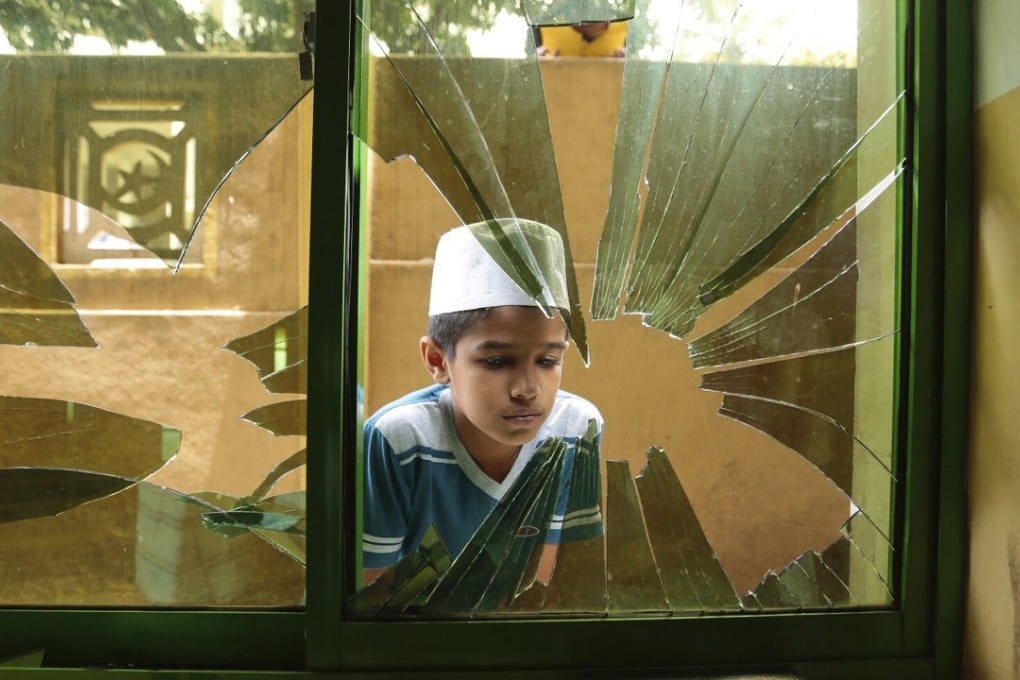 A Sri Lankan Muslim boy looks through the broken window of a vandalised Mosque in Digana, Kandy, Sri Lanka. Photo: AP