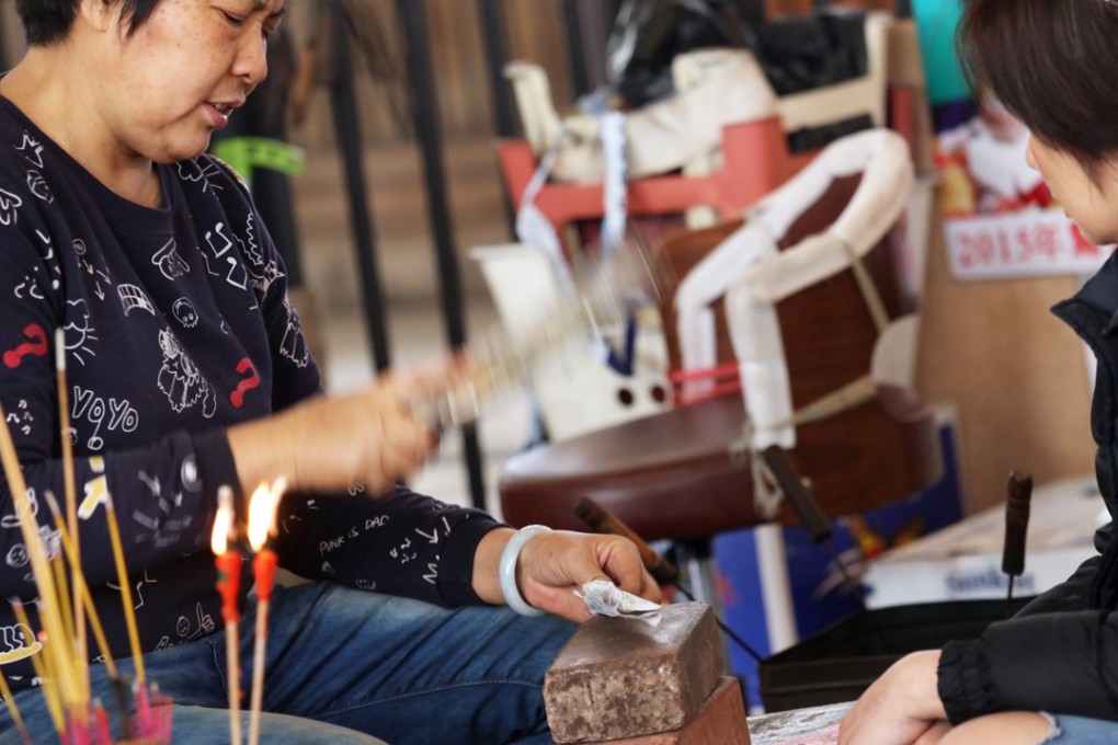A practitioner pounds a shoe as part of a ritual to cast a spell on a person. Photo: Felix Wong