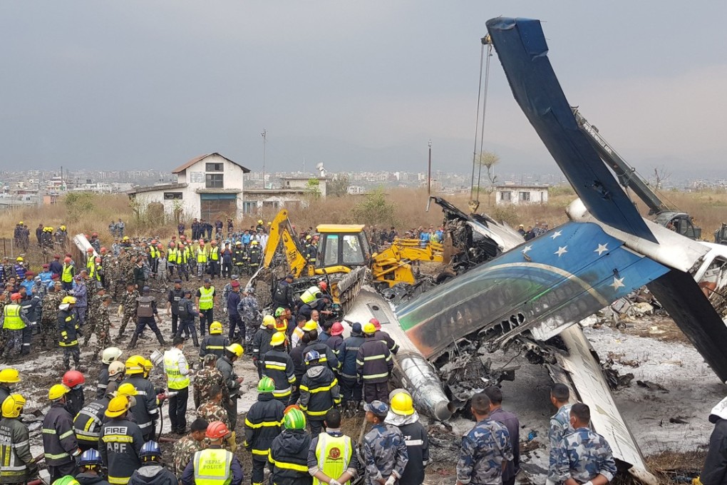 Nepalese rescuers stand near the passenger plane from Bangladesh that crashed at the airport in Kathmandu, Nepal. Photo: AFP