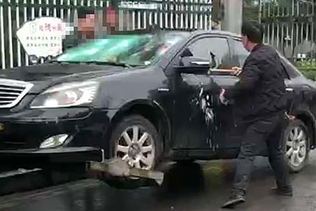 A man in central China attacked his car with a hammer as police were preparing to tow it away. Photo: Thepaper.cn