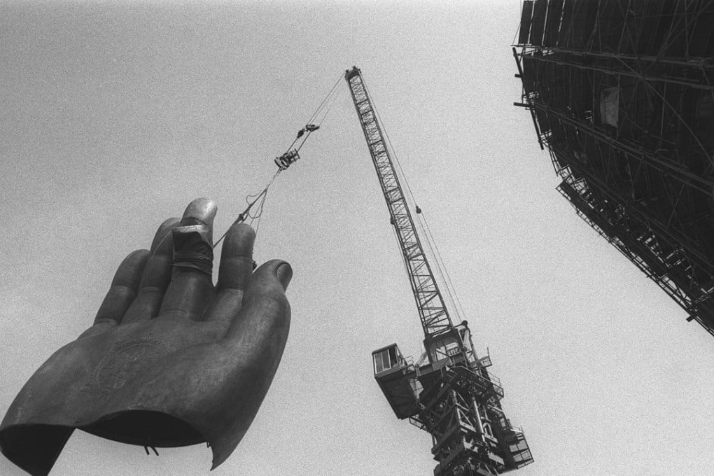 A crane hoists one of the statue’s giant hands towards the main body of the Big Buddha (right) during its construction at the Po Lin Monastery on Hong Kong’s Lantau Island. Photo: SCMP