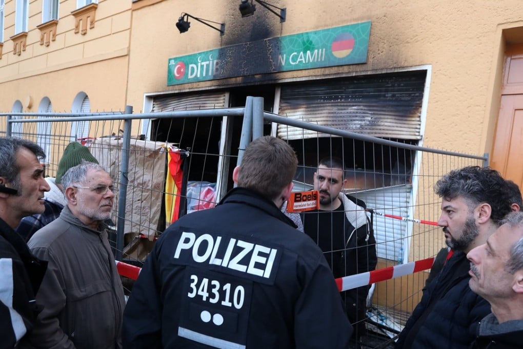 A policeman talks with a member of the Koca Sinan Camii mosque after it was destroyed by a fire at night, in Berlin, Germany, on March 11, 2018. Photo: EPA-EFE