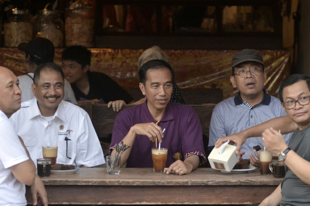 Indonesia President Joko Widodo (centre) sits with his ministers while visiting a cafe in Kuta beach, Bali. Indonesians could be jailed for criticising national politicians under a new law that came into force on Thursday. Photo: Reuters