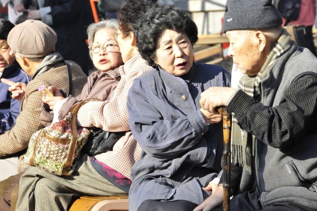 Elderly people sit in the sun and chat each to other at Tokyo's Sugamo district. Photo: AFP/Yoshikazu TSUNO