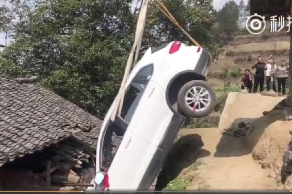 The car had to be pulled free after it became wedged in a gap between the hill and the roof of the house. Photo: Qq.com