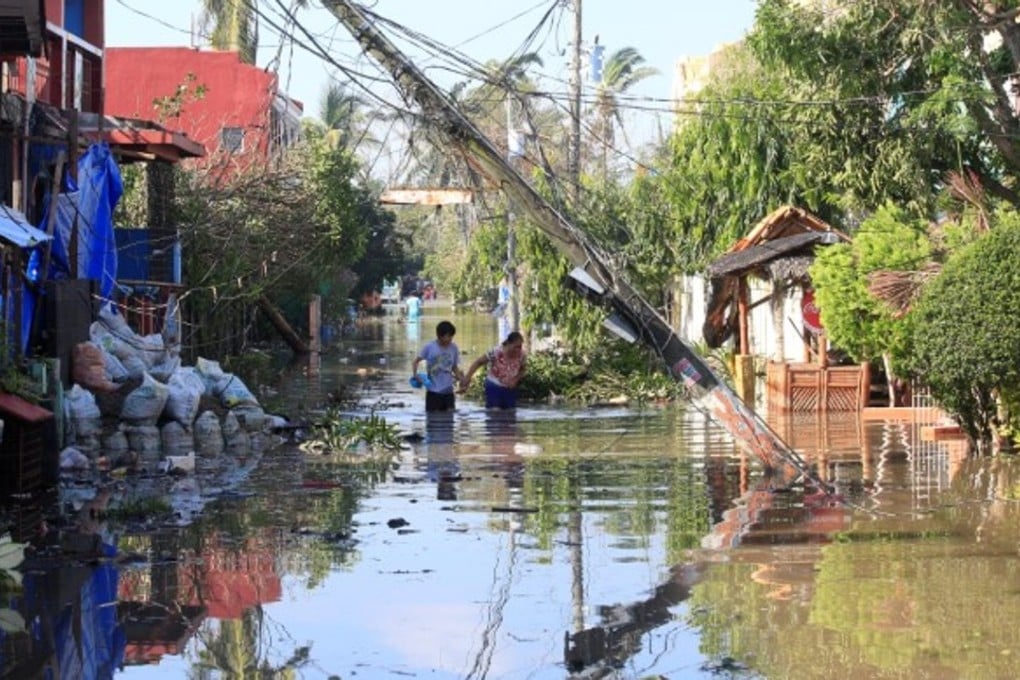 Residents wade across a flooded street caused by a typhoon. Photo: Reuters