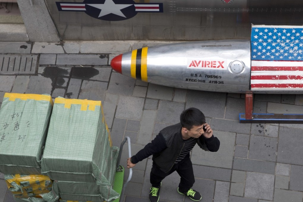 A delivery man calls for directions while pulling a cart of goods past a US apparel store in Beijing on Friday. China is in a spiralling trade dispute with the United States. Photo: AP