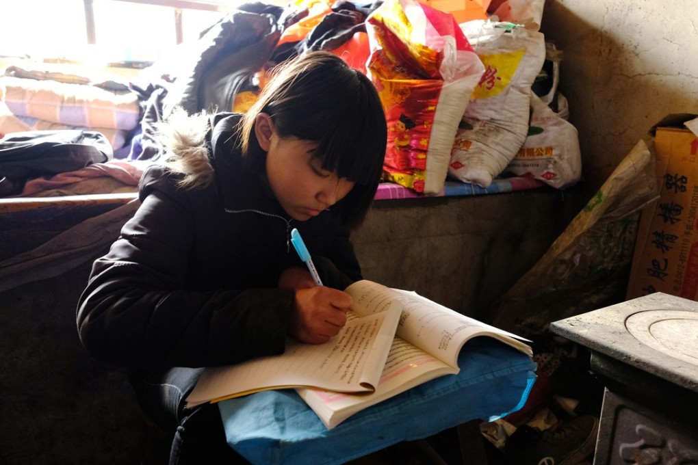 On weekends at home, 15-year-old Little Zhang sits on a tree stump to study, using a stool as a desk. Photo: Lea Li