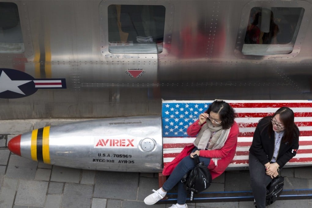 Chinese women sit on a bench with a US flag theme outside an apparel store in Beijing on March 23. China announced a US$3 billion list of US goods including pork, apples and steel pipes that may be hit with higher tariffs in a spiralling trade dispute with President Donald Trump. Photo: AP