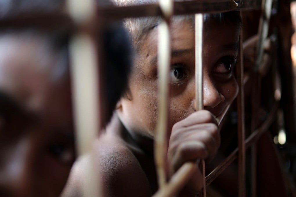 A Rohingya refugee child looks through the fence at a refugee camp in Cox’s Bazar. Photo: Reuters