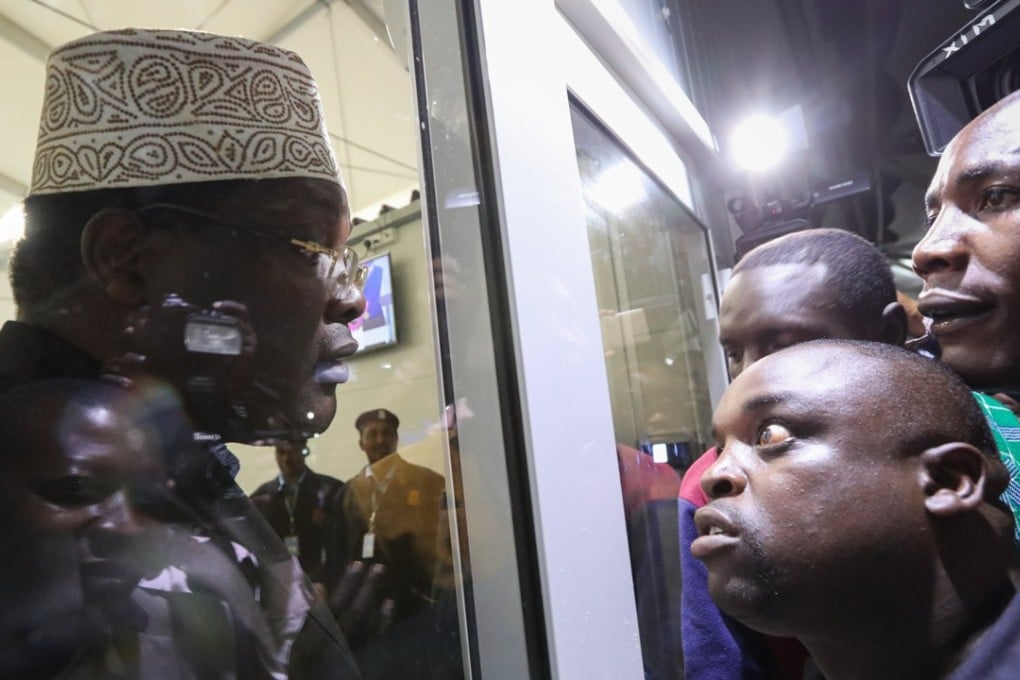 Kenyan opposition figure Miguna Miguna (L) talks to his supporters (R) from a closed door after he was detained at immigration upon his arrival at the Jomo Kenyatta International Airport in Nairobi. Photo: EPA