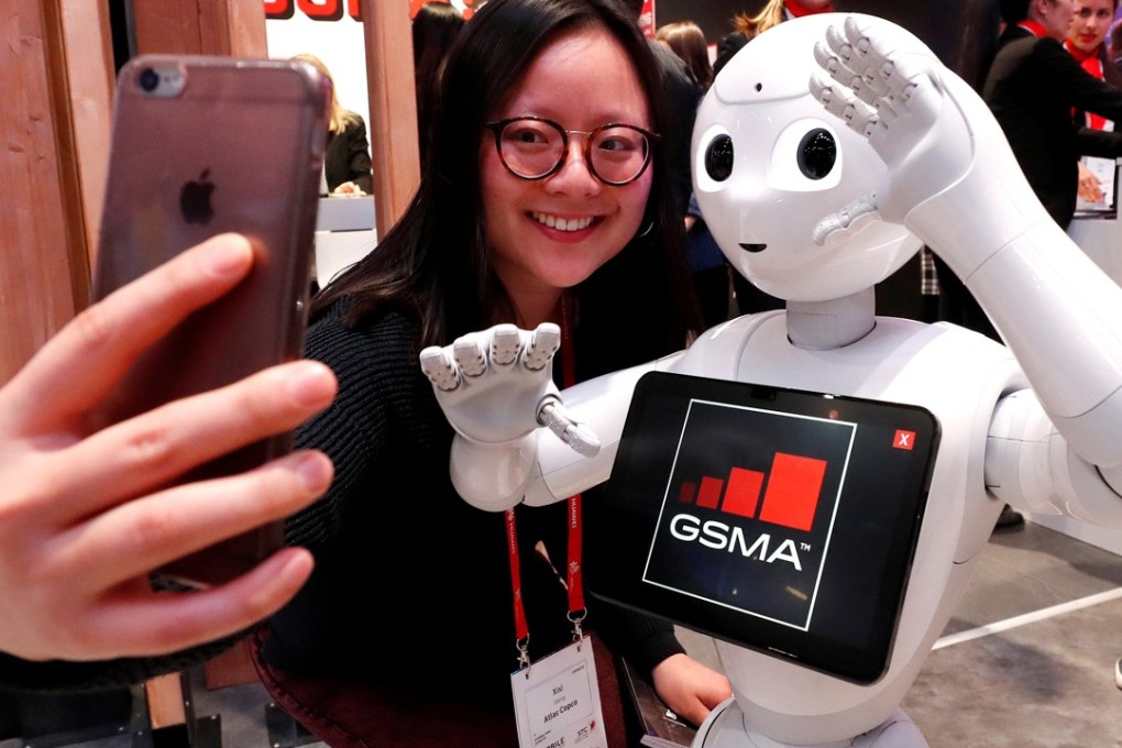 A visitor to the Mobile World Congress in Barcelona, Spain, takes a selfie with a robot from SoftBank Robotics, on February 28. Photo: Reuters