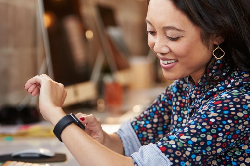 A businesswoman looks at her watch while at her desk. In New Zealand, a trustee firm is trialling a four-day work week, meaning employees have a third day off. And the experiment could catch on. Photo: Alamy Stock Photo