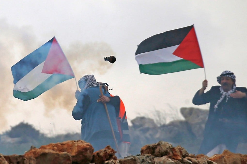Palestinian men wave their national flag during a demonstration in the Israeli occupied West Bank on March 30. Israeli troops opened fire on the protesters, killing 16. Photo: AFP