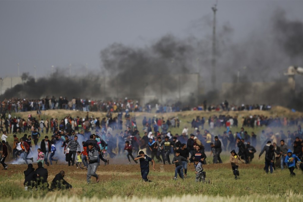 Palestinians scatter as tear gas canisters fired by Israeli troops fall during a demonstration near the Gaza Strip border with Israel, in eastern Gaza City, on Friday. Palestinians clashed with Israeli troops along the border Friday morning as thousands gathered there for mass sit-ins led by the militant Islamic group Hamas, which rules the territory. Photo: AP