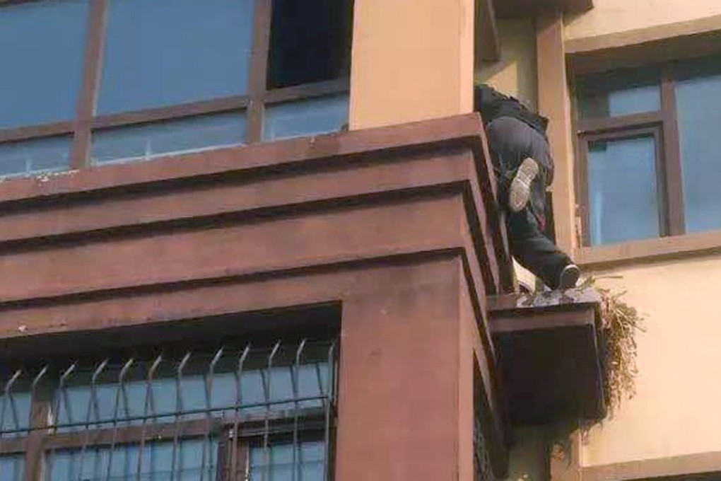 A cool-headed courier in Harbin, northeastern China, scales a block of flats to rescue an elderly and infirm resident from her burning home. Photo: Qq.com