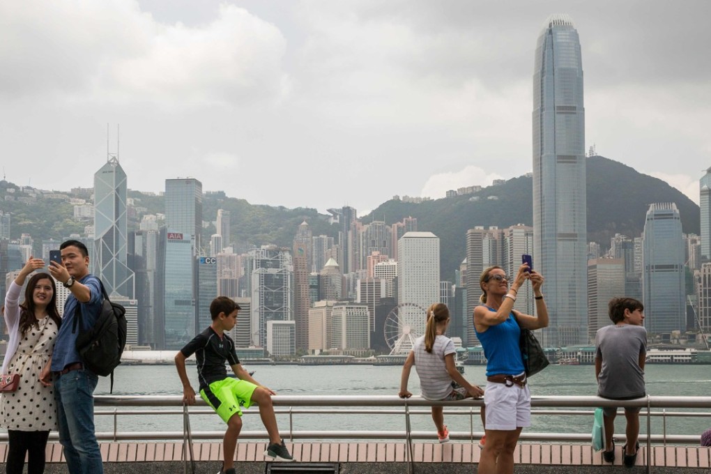 Visitors enjoy a warm day at the Tsim Sha Tsui observation deck overlooking Victoria Harbour. Photo: AFP