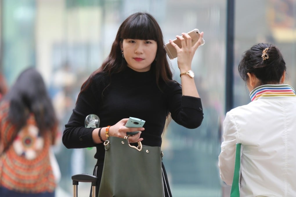 A woman listens to a voice message on one phone while holding another, in Causeway Bay. Telemarketers should get the message when their services are not wanted. Photo: Xiaomei Chen