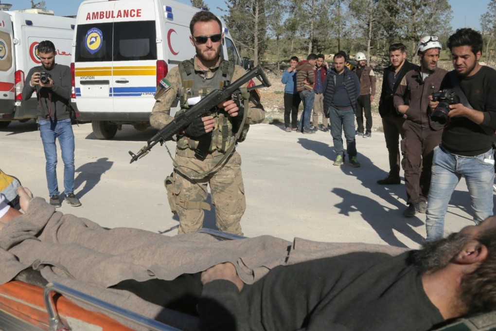 A pro-government soldier looks at an injured Syrian man as buses carrying Jaish al-Islam fighters and their families from the former rebel bastion's main town of Douma arrive at the Abu al-Zindeen checkpoint controlled by Turkish-backed rebel fighters near the northern Syrian town of al-Bab, on Wednesday. Photo: AFP