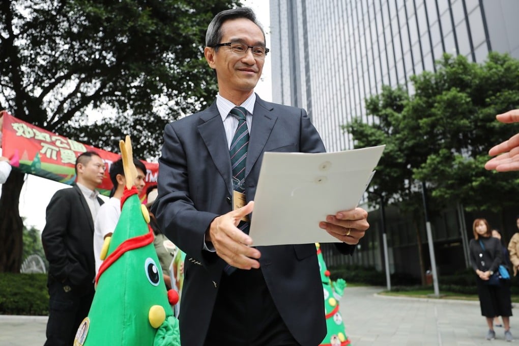 The chairman of the Task Force on Land Supply, Stanley Wong Yuen-fai, receives petition letters from Greenpeace campaigners urging the task force to safeguard country parks, outside the Hong Kong government headquarters, in Admiralty last December 5. Photo: Winson Wong