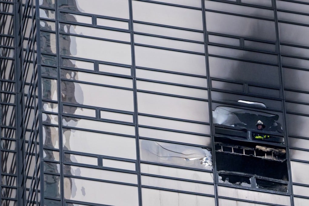 A firefighter looks out from the window of the damaged apartment in Trump Tower. Photo: AP
