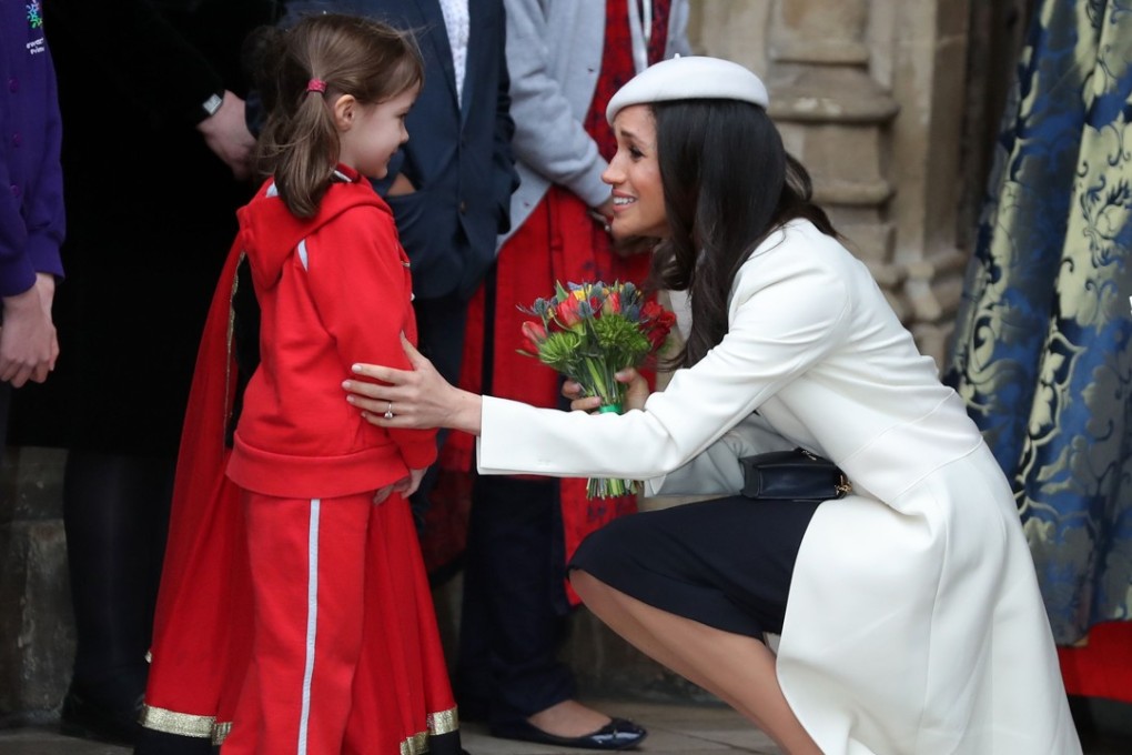 Meghan Markle, fiancée of Britain's Prince Harry receives a posy of flowers from a young girl after attending a Commonwealth Day Service at Westminster Abbey in central London. Photo: AFP