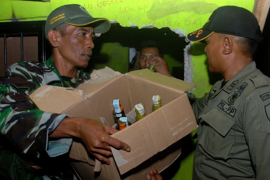 Indonesian police remove bottles of illegal alcohol from a house in Cicalengka district in West Java province on Sunday. More than 60 Indonesians have died from drinking bootleg liquor, police said. Photo: AFP