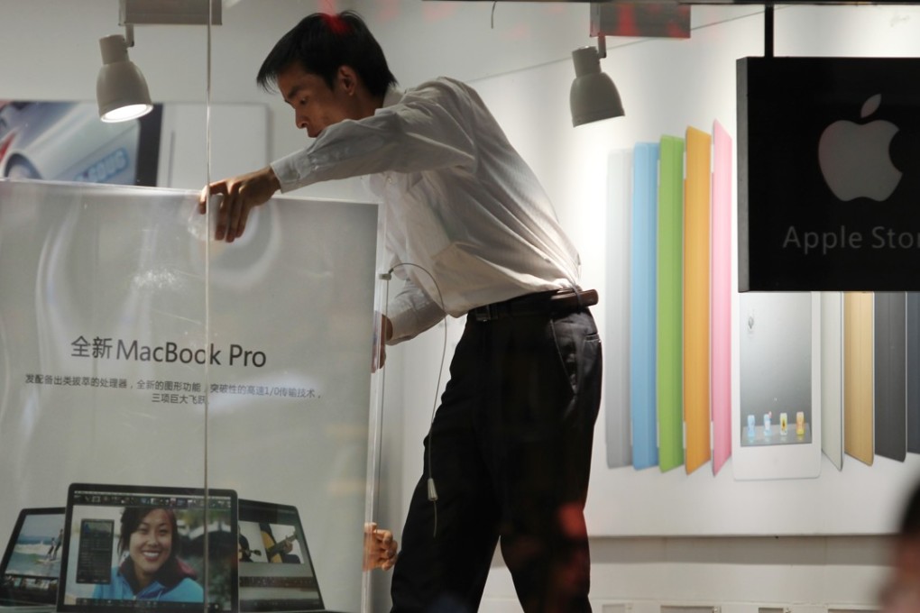 A staff member taking down a product poster on July 21, 2011, in a shop in the Yunnan provincial city of Kunming, which disguises itself as a bona fide Apple store, by copying everything from the genuine shop’s logo, decor down to the uniform and identification tags. Photo: SCMP/Simon Song