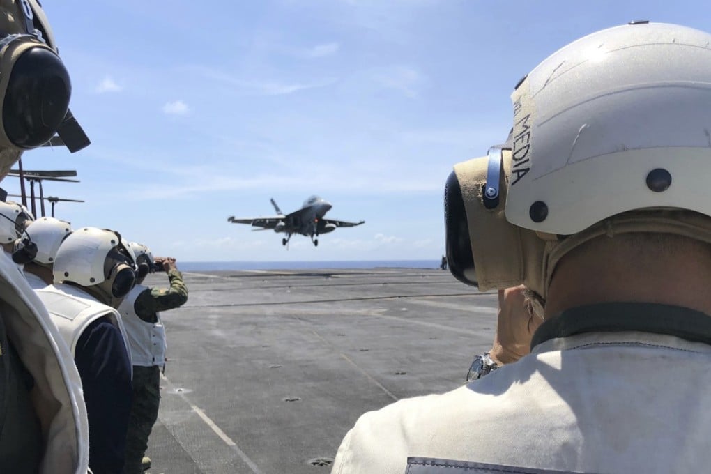 Philippine generals and journalists watch from the deck of the US aircraft carrier Theodore Roosevelt as a US fighter jet lands on Tuesday, in international waters off South China Sea. Photo: AP