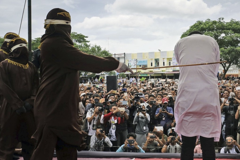 A Shariah law official whips a man convicted of gay sex during a public caning outside a mosque in Banda Aceh, Aceh province Indonesia. Photo: AP