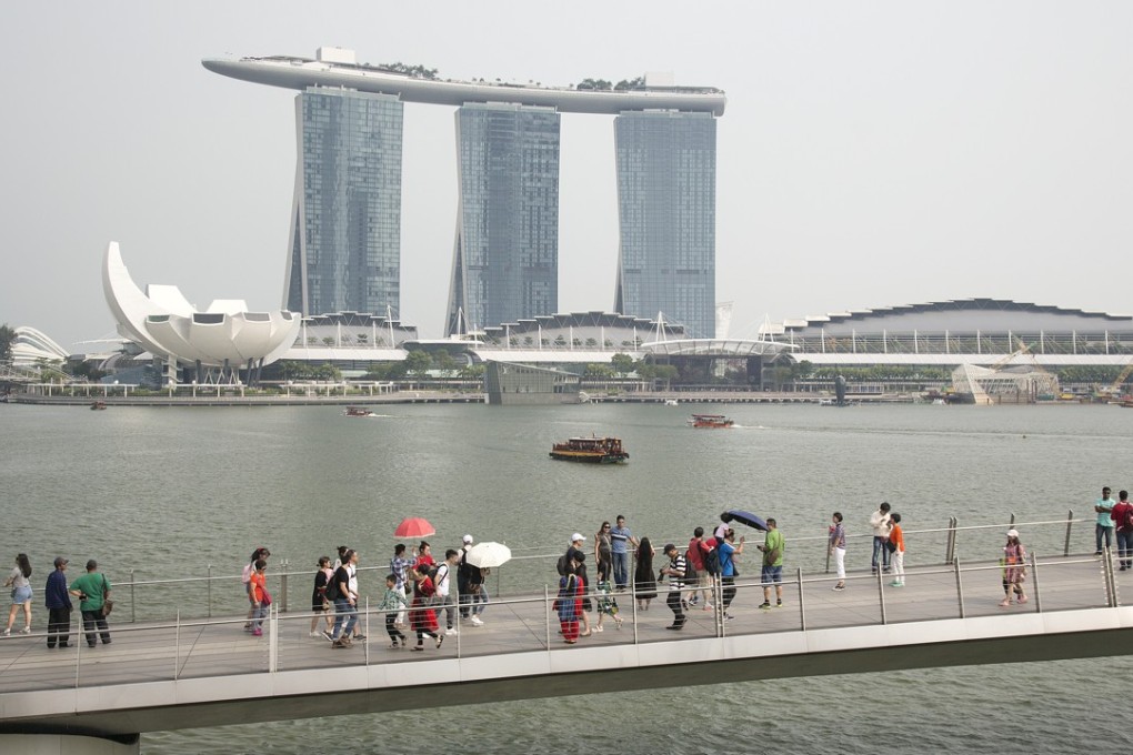 Pedestrians walk on the Jubilee Bridge with the Marina Bay Sands hotel and casino in the background in Singapore. Photo: Bloomberg