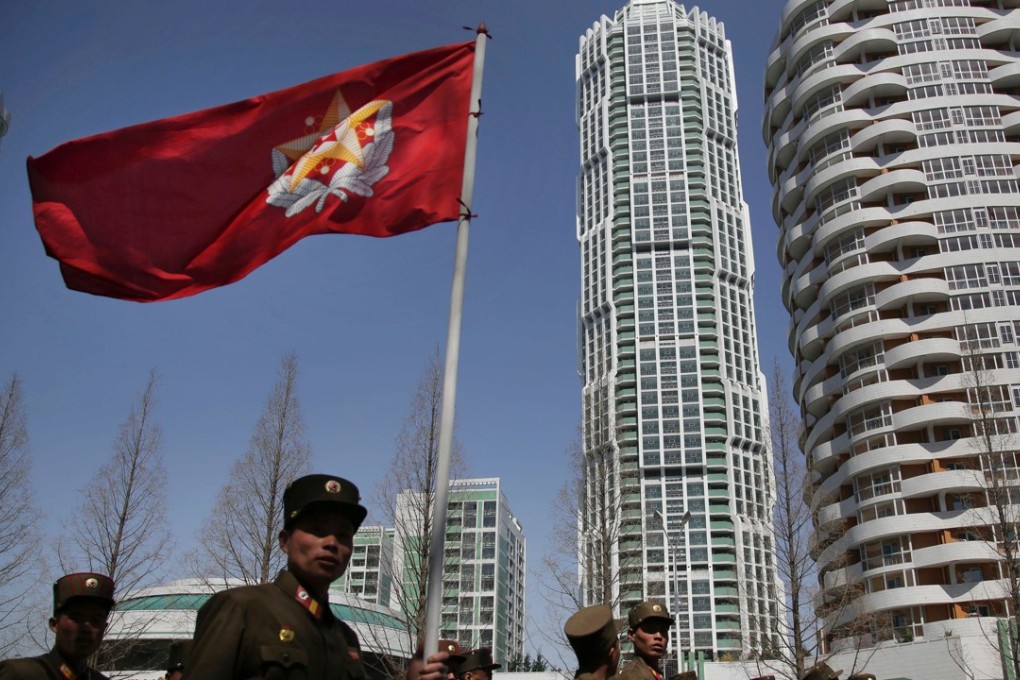 North Korean soldiers carry the Korean People’s Army flag as they walk past residential buildings along Ryomyong street in Pyongyang. Photo: AP