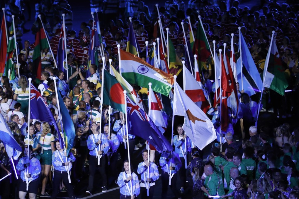 The flags of participating nations are marched into Carrara Stadium for the closing ceremony. Photo: AFP
