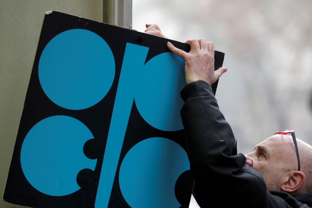 A man fixes a sign with Opec's logo next to its headquarters' entrance before a meeting of OPEC oil ministers in Vienna, Austria, on November 29, 2017. Photo: Reuters