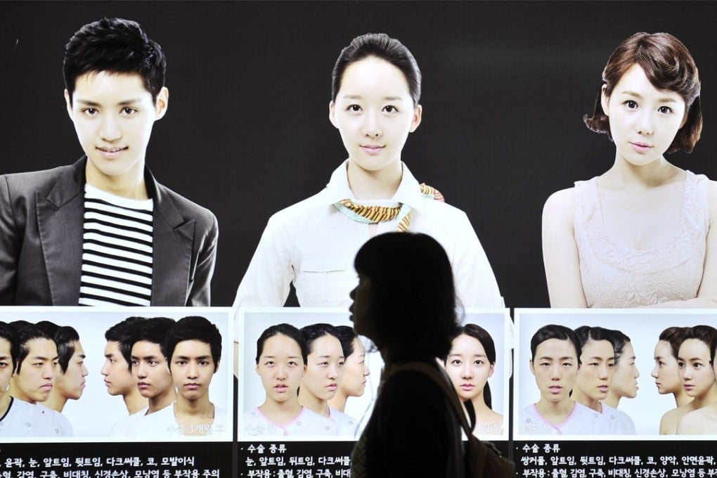 A South Korean woman walks past a street billboard advertising double-jaw surgery at a subway station in Seoul. Photo: AFP